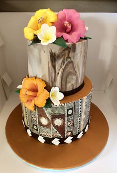 a three tiered cake decorated with flowers on top of a brown and white plate