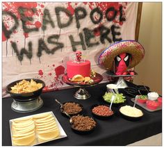 a table topped with lots of food next to a sign that says deadpool mash