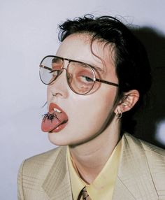 a man with fake tongue sticking out from his mouth wearing glasses and a suit jacket