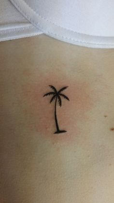 a small palm tree tattoo on the back of a woman's left ribcage