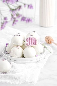 white chocolates with pink frosting in a bowl on a table next to flowers