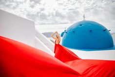 a woman in a red dress standing on the roof of a building with blue domes