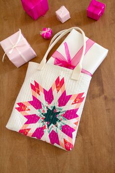 a pink and white bag sitting on top of a wooden table next to small presents