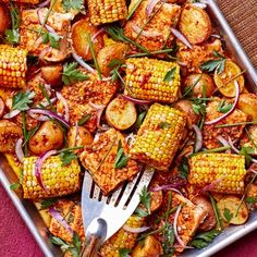 corn on the cob with potatoes and onions in a baking pan, ready to be eaten