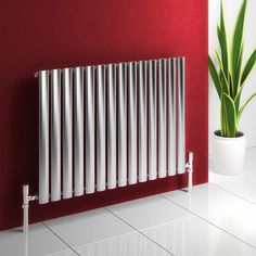 a white radiator sitting on top of a red wall next to a potted plant