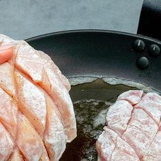 two pieces of meat being cooked in a frying pan