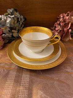 a cup and saucer sitting on top of a table next to some pink flowers