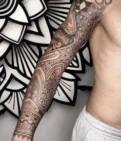 a man's arm with tattoos on it and an ornamental design in the background