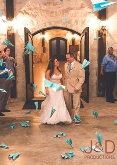 a bride and groom standing in front of a doorway surrounded by blue origami birds