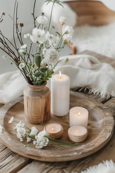 some white candles are sitting on a wooden tray