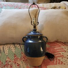 a large blue vase sitting on top of a bed next to a pillow and lamp