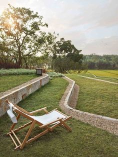 a lawn chair sitting on top of a lush green field next to a stone wall