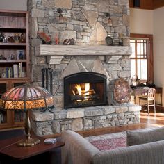 a living room with a stone fireplace and bookcases on the wall above it