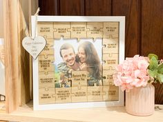 a personalized puzzle frame with a heart hanging on the wall next to a vase filled with flowers