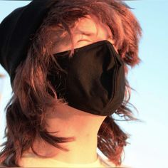 a woman wearing a black face mask on top of her head and hair blowing in the wind