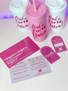 two pink cups with straws next to each other on a white counter top and some stickers