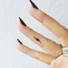 a woman's hand with black nail polish and a lightning bolt tattoo on it