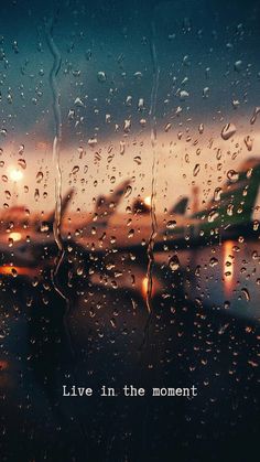 rain drops on a window with the words live in the moment