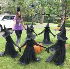 a woman standing in the grass next to some black witches