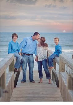 a family standing on a pier with the ocean in the background