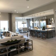 a living room filled with furniture next to a kitchen and dining room table in front of a large window