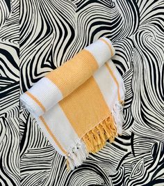 an orange and white towel laying on top of a black and white pattern