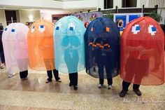 several people standing in line with plastic coverings on their heads and body, all wearing costumes