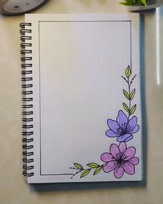 an open notebook with flowers drawn on it next to a clock and plant potted in the background