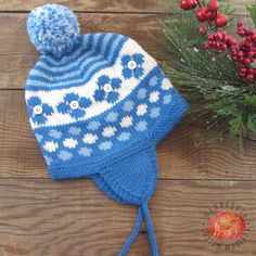 a blue and white knitted hat sitting on top of a wooden table next to berries