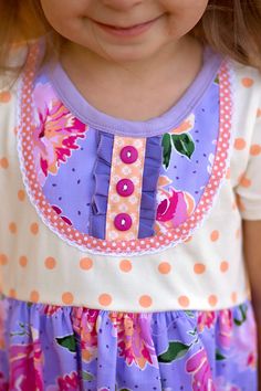 If this dress looks familiar, it’s because it is! It’s a remake of one of my most popular dresses that YOU designed! This is a knit bodice dress in peach polka dot that is accented by a floral bib with all the trimmings- buttons and ruffles and lace! The full lilac floral skirt has 2 outside pockets with peach buttons and a peach ruffled hem. This handmade beauty will turn heads with bright bold floral color and fantastic attention to detail! Available in sizes 2-12 Don’t forget the matching bow Dress Looks, Bodice Dress, Handmade Beauty Products, Popular Dresses, Floral Color, Set Dress, Floral Skirt, Knit Dress, Plum