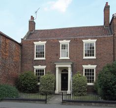 an old brick house with white trim and black gated in area next to it