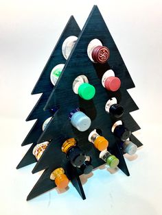 a wooden christmas tree with many different bottles on it's sides and the top one is made out of black plywood