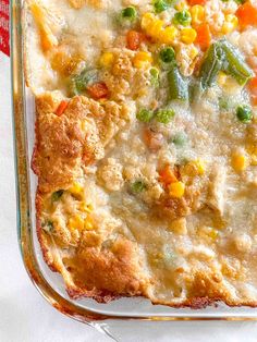 a casserole dish with vegetables and meat in it on a white table cloth