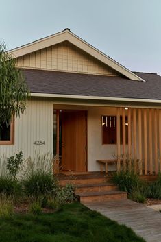 a small white house with wooden doors and steps leading up to the front door area