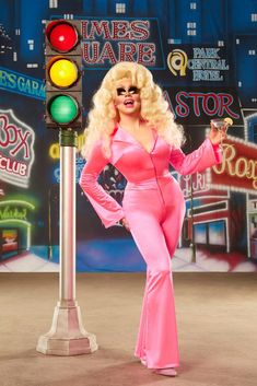 a woman in pink is standing next to a traffic light and posing for the camera