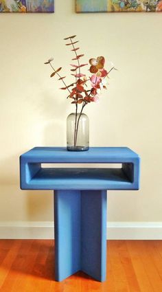 a vase with flowers sitting on top of a blue table in front of a wall