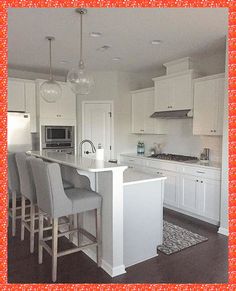 a large kitchen with white cabinets and gray bar stools in front of an island