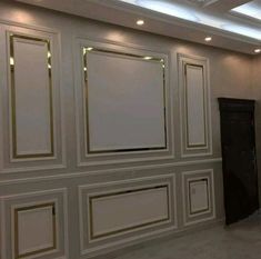 an empty room with white walls and gold trim around the doors, lighting from recessed lights