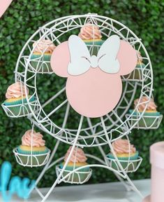 cupcakes with pink frosting and white bows are on top of a ferris wheel