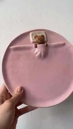 a person holding a pink plate with a teddy bear on it