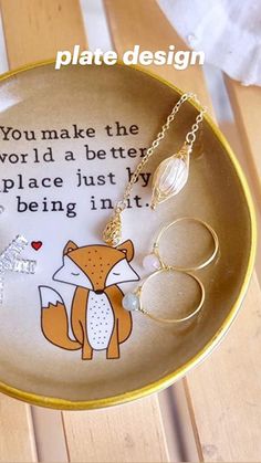 a plate with some rings on it and a fox necklace hanging from the bottom one