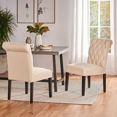 a dining room table with two chairs and a potted plant