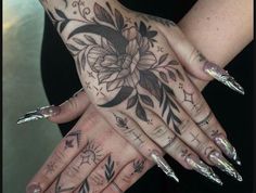 a woman's hands with tattoos on them and nails in the shape of flowers