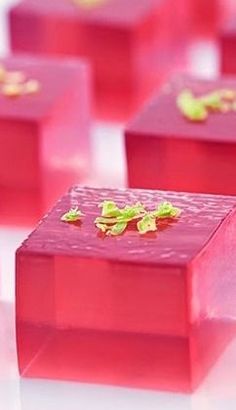 several square pieces of pink colored food with green leaves on the top and bottom part