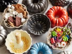 many different types of bundt cakes and cake pans on a table with candy