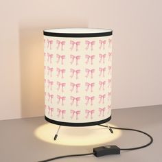 a lamp with a pink bow on it next to a black and white charger