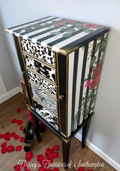 a black and white striped cabinet with red roses on the floor next to it is a pair of high heel shoes