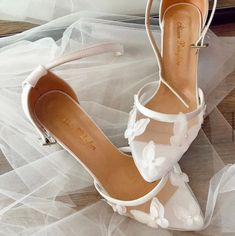 a pair of white shoes sitting on top of a wooden floor next to a veil