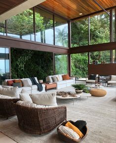 a living room filled with lots of furniture next to tall windows and plants on the wall