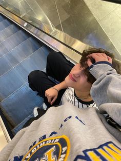 a boy sitting on an escalator with his head in his hands and eyes closed